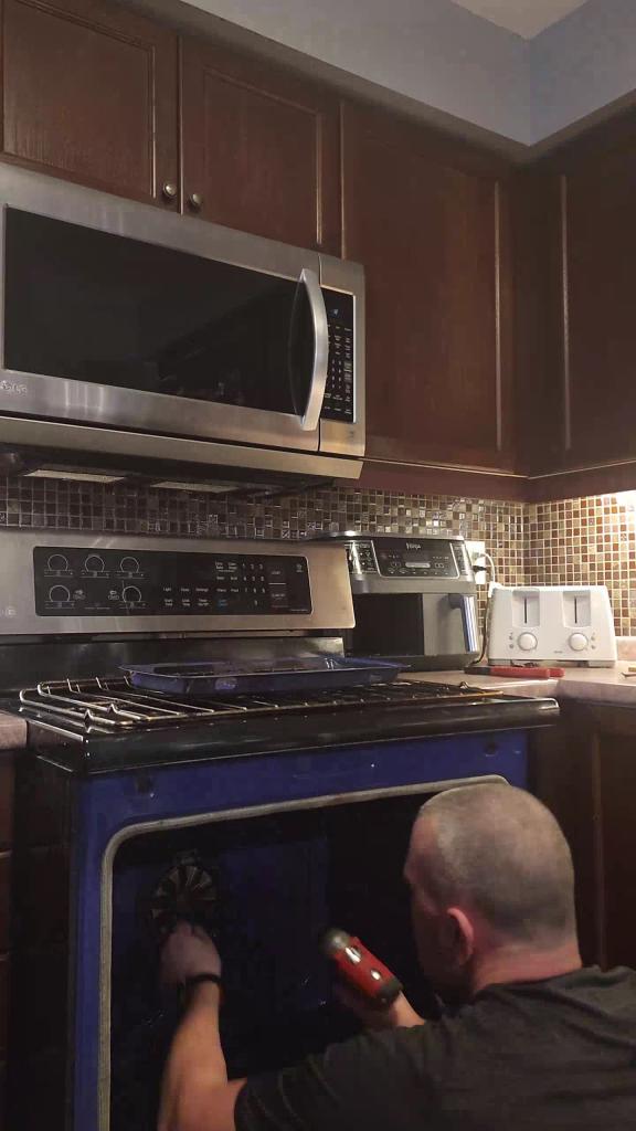 EZFIX technician repairing broken oven hinge for proper oven door alignment and safety