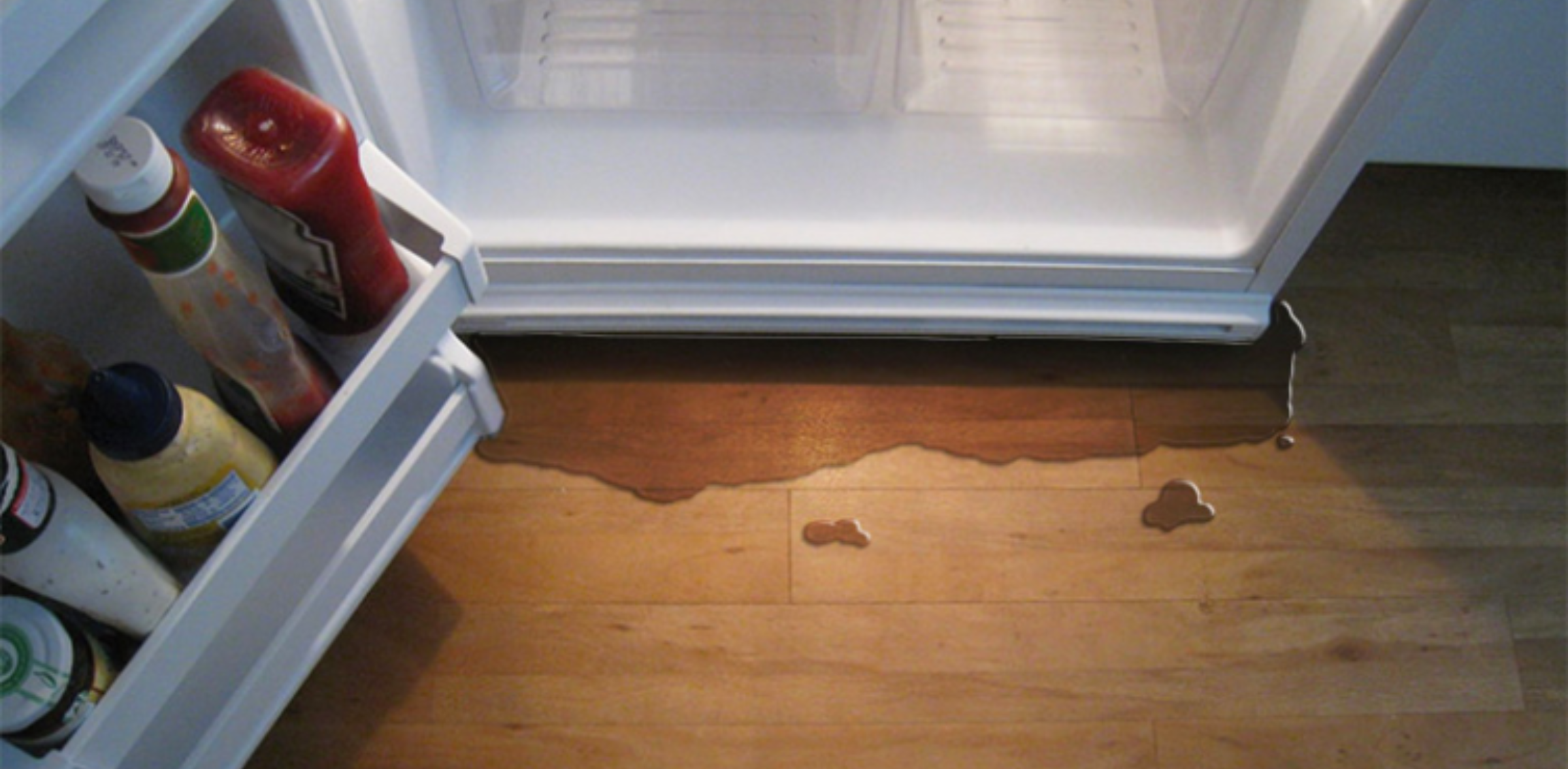 A professional repairman fixing a leaking refrigerator, focusing on sealing the door gasket to prevent water leaks.